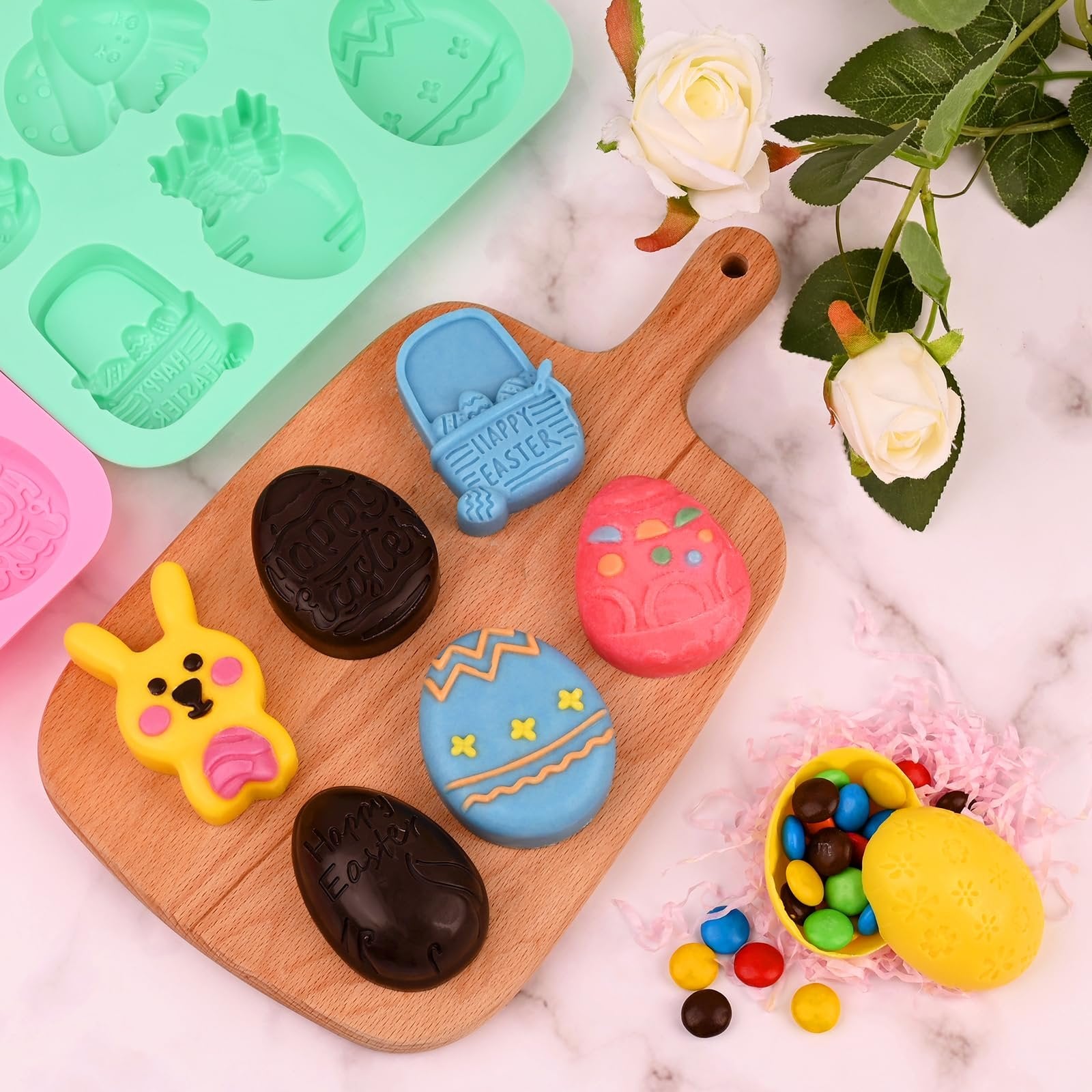 Easter-themed chocolate molds and candies arranged on a wooden board and marble surface, with decorative roses.