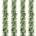 Four strands of faux eucalyptus garland with white flowers on a white background