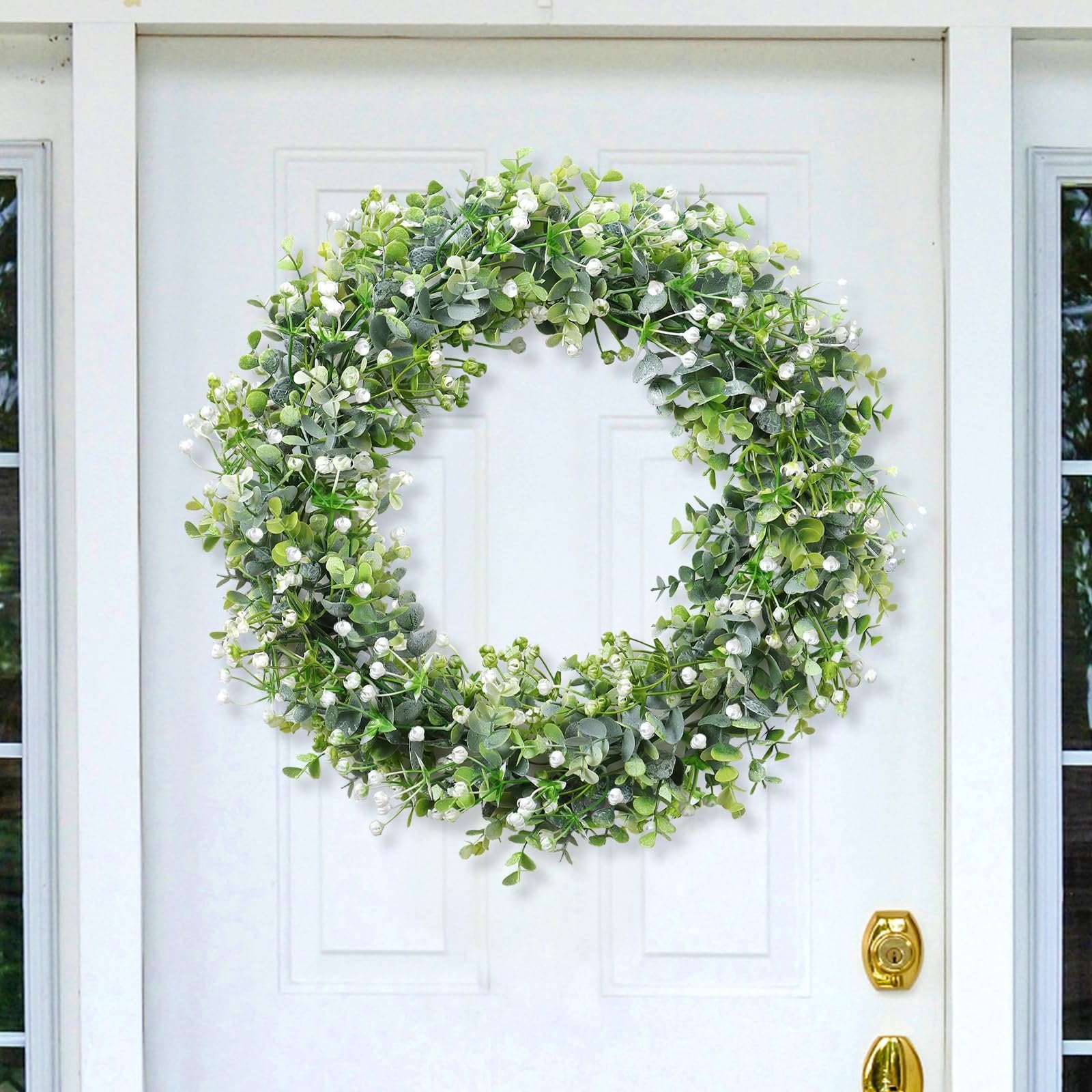 Faux eucalyptus garland with white flowers hanging on a white door