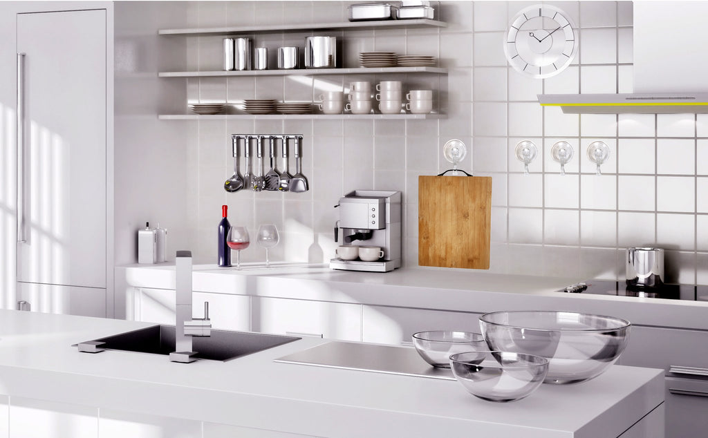 Four clear suction cup hooks attached to a tiled wall in a modern kitchen, holding a wooden cutting board.