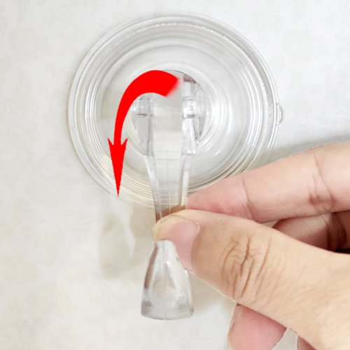 Hand demonstrating how to attach a clear polycarbonate suction cup hook to a tiled surface with a red arrow indicating rotation.