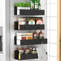 Four black magnetic spice racks mounted on a refrigerator, holding various jars, bottles, and an oven mitt.