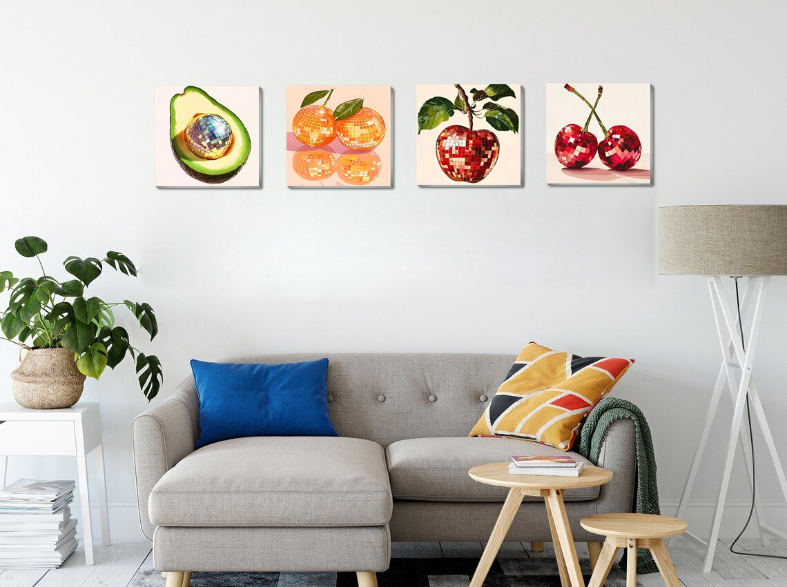 Four framed paint by number canvases depicting disco ball fruits hanging on a wall above a sofa.