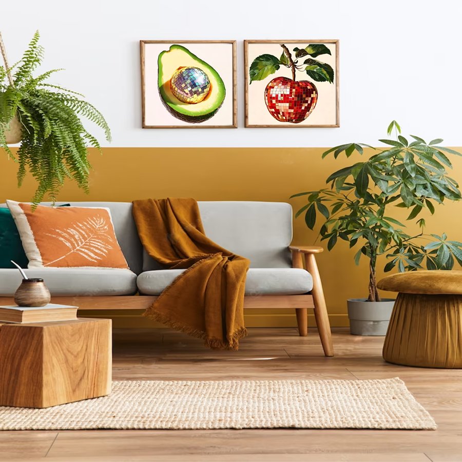 Living room scene with two framed art prints of a disco ball avocado and a disco ball apple above a sofa.