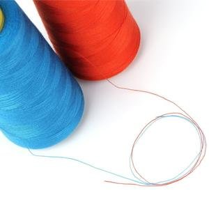 Two large spools of blue and orange sewing thread with loose strands on a white background