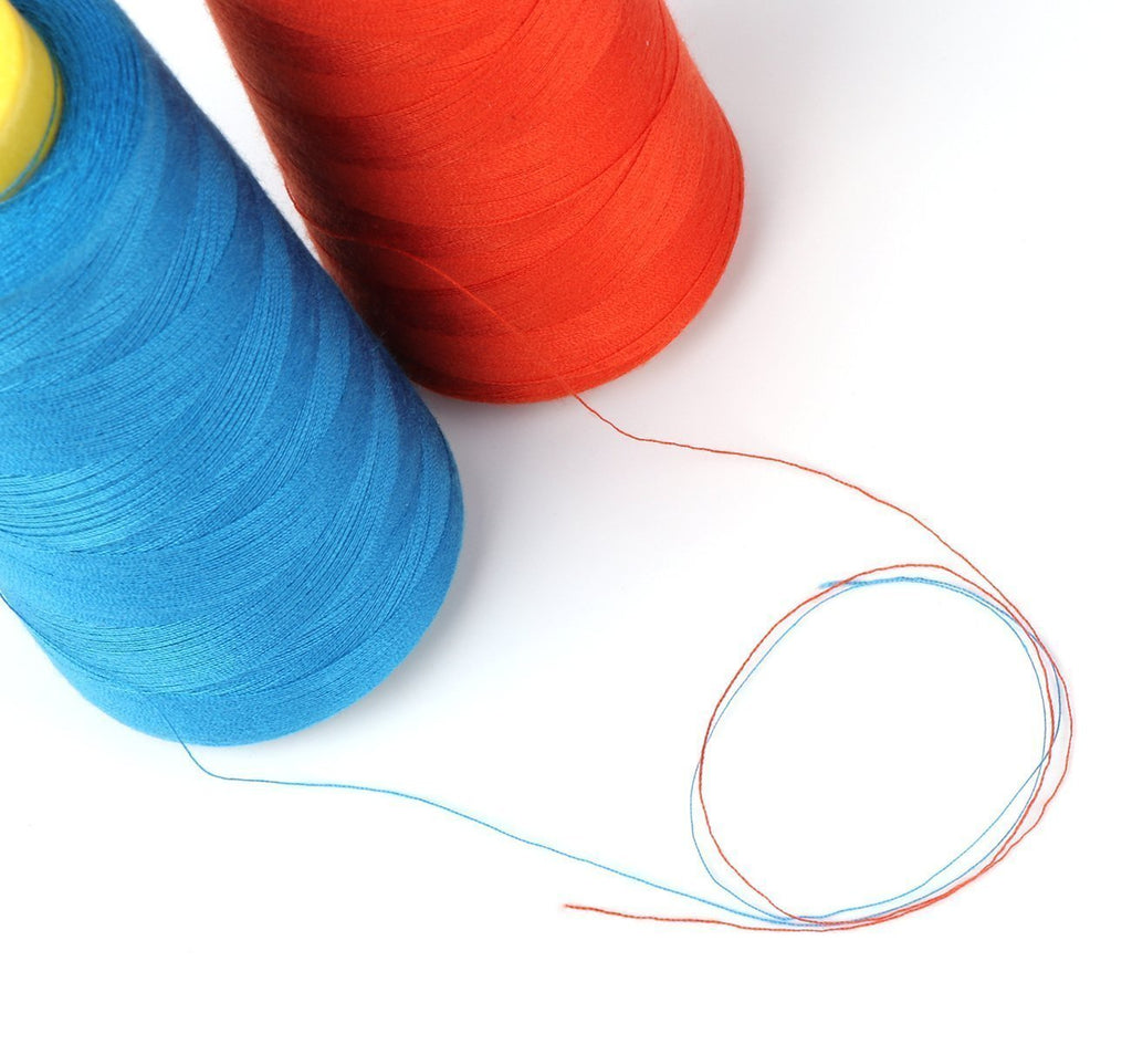 Two spools of polyester sewing thread, one blue and one orange, with loose threads on a white background.