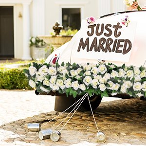 White artificial rose vine garlands decorating the back of a wedding car with a 'Just Married' sign