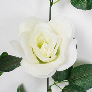 Close-up of a white artificial rose garland with green leaves against a white background.