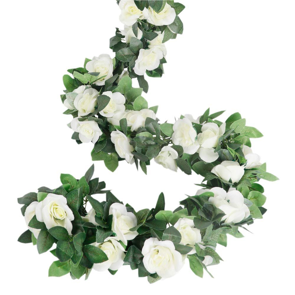White artificial rose vine garland with green leaves, coiled on a white background.