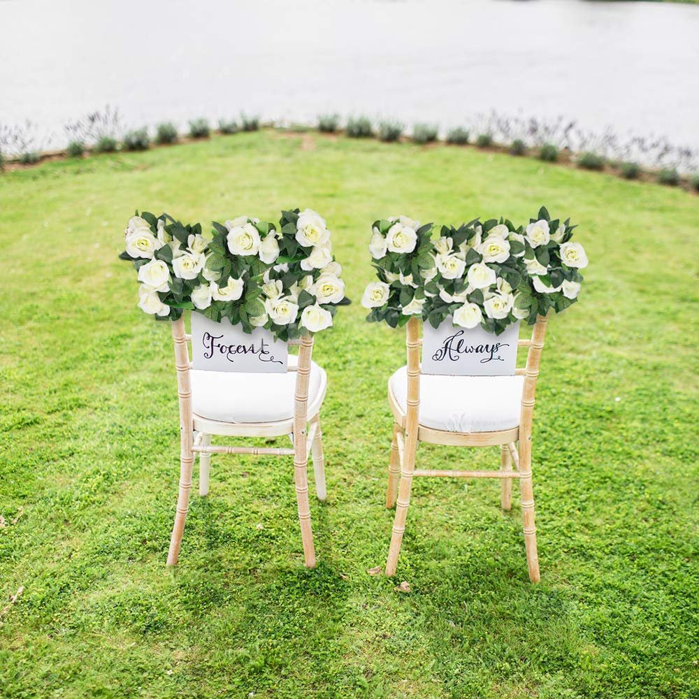 Two chairs decorated with white rose garlands, one with 'Forever' and the other with 'Always' signs.