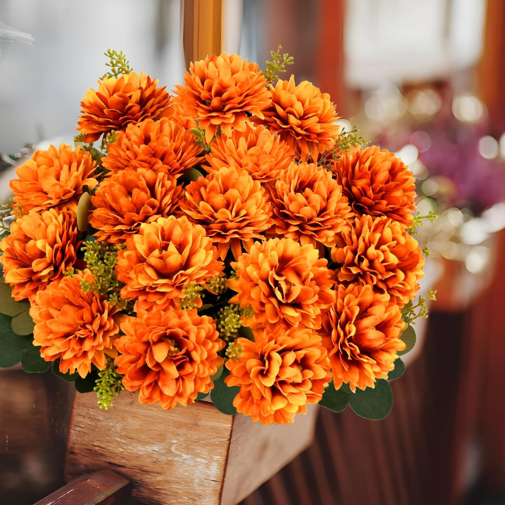 Arrangement of orange artificial mums in a wooden planter, front view.