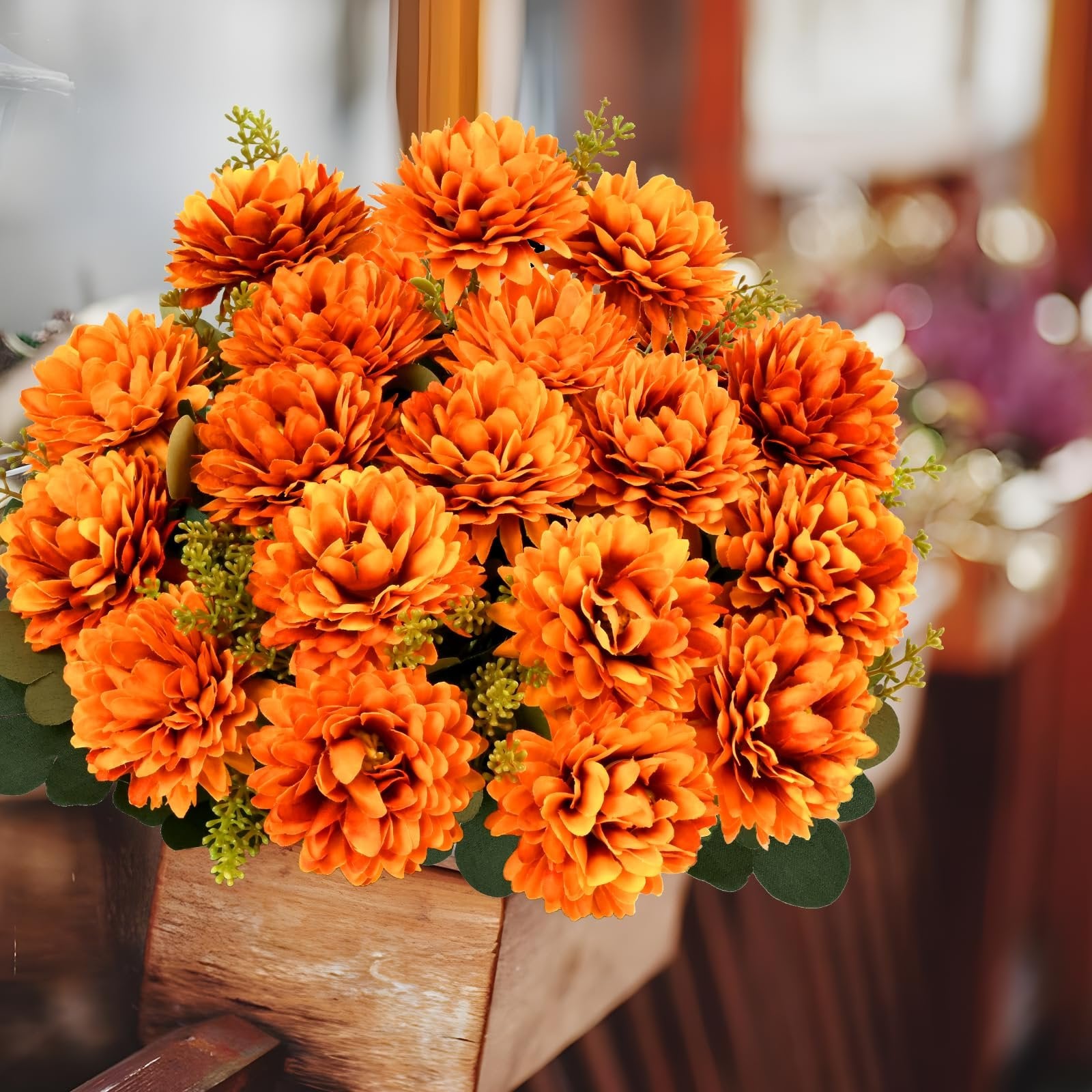 Arrangement of orange artificial mums in a wooden planter, front view.