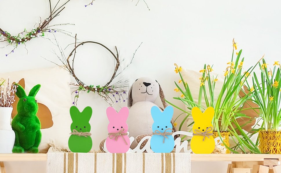 Four pastel wooden bunny decorations with twine bows on a shelf with Easter decor