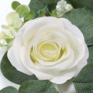 Close-up of a white artificial rose with green eucalyptus leaves and small white flowers, part of a garland.