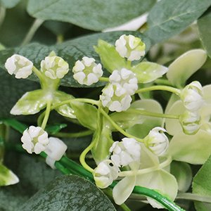 Close-up of artificial eucalyptus garland with white gypsophila flowers and green plastic stems.