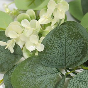 Close-up of artificial eucalyptus garland with white silk flowers and green leaves.