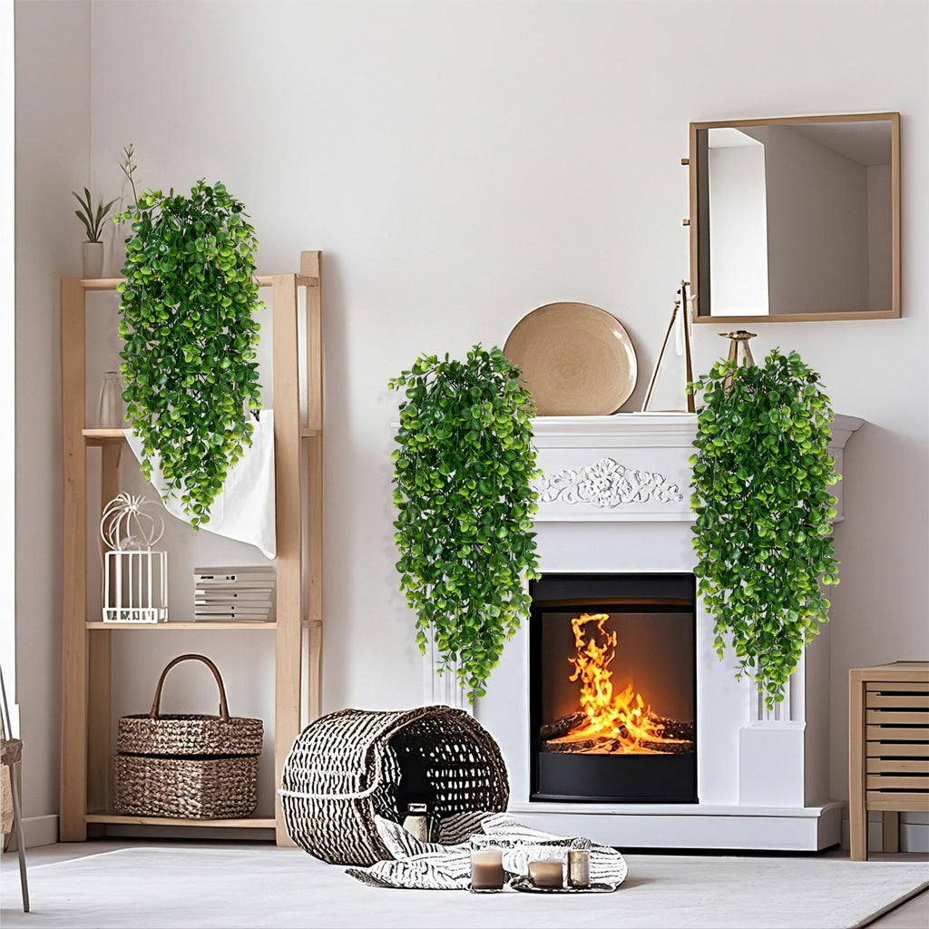 Four artificial eucalyptus hanging plants draped around a fireplace and on a shelf.