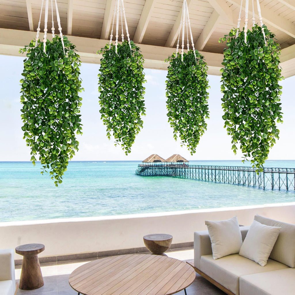 Four artificial hanging eucalyptus plants with macrame hangers on a balcony overlooking the ocean