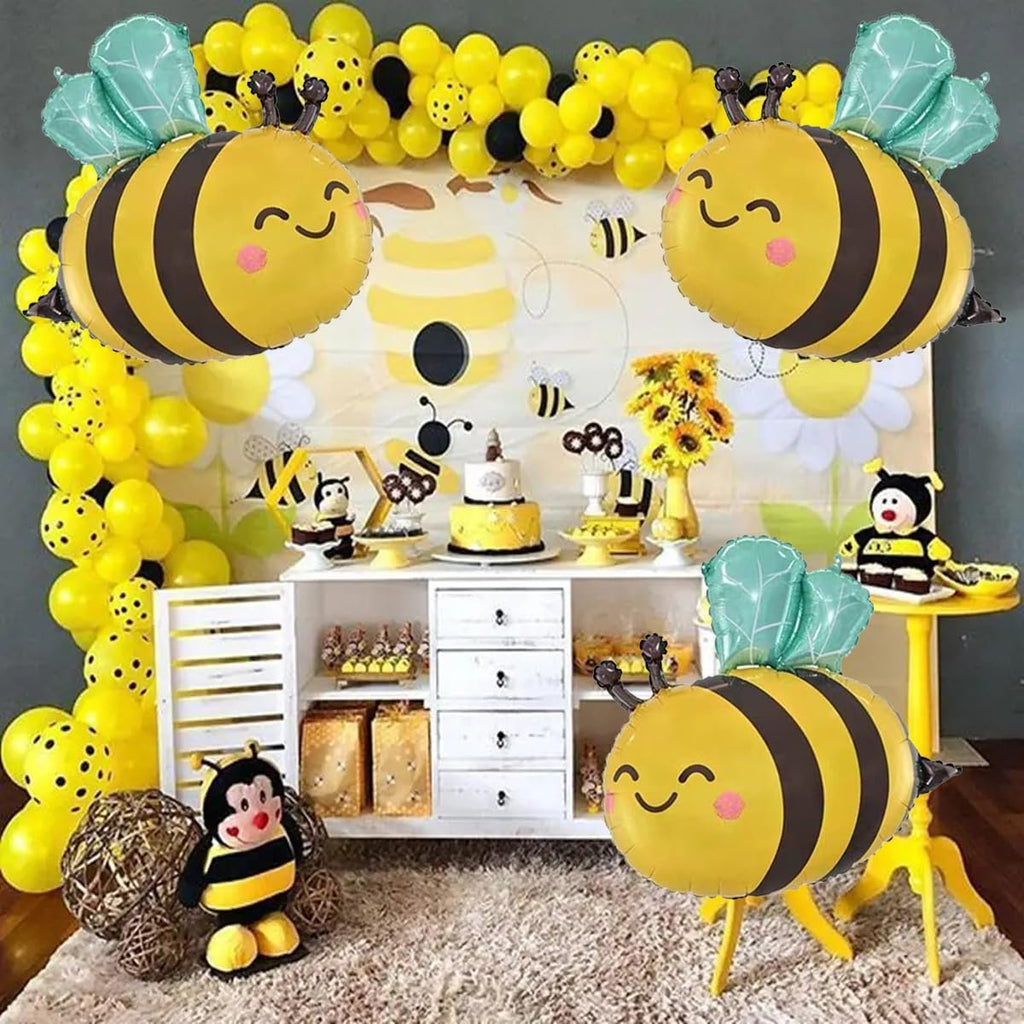 Bee-themed party scene with balloons, cake, and bee-shaped foil balloons in foreground.