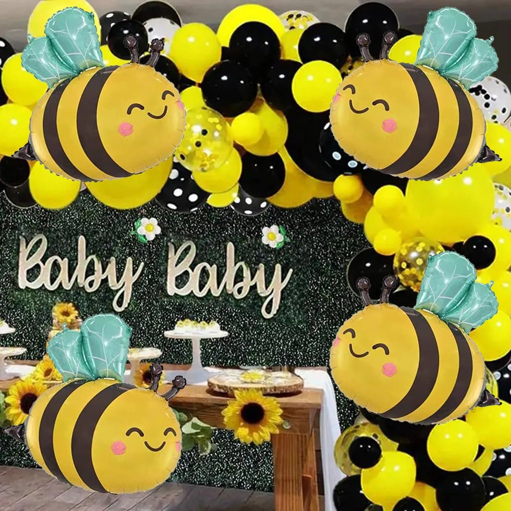 Four bee-shaped foil balloons arranged around a party setup with a 'Baby Baby' sign and yellow and black balloons.