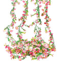 Four strands of artificial daisy flower garland with pink and rose red flowers and green leaves, displayed against a white background.