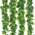 Four artificial monstera leaf vines with green fabric palm leaves and bendable plastic stems against a white background.