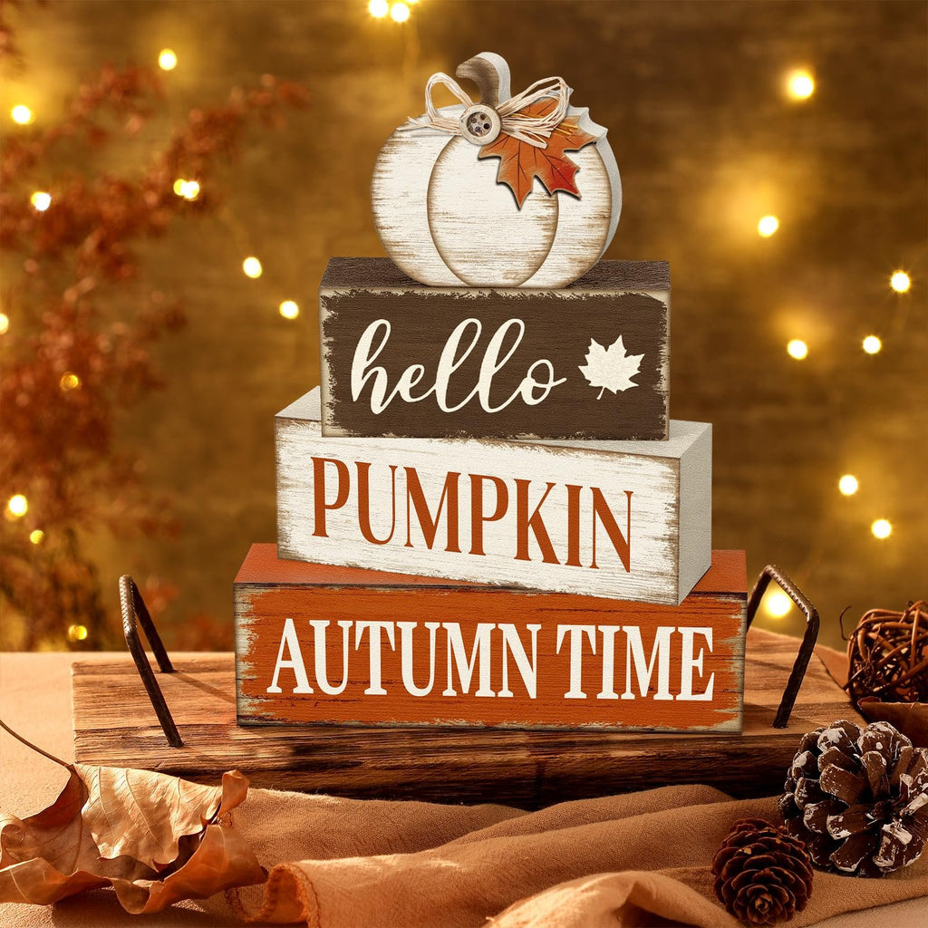 Stack of three wooden autumn signs with a decorative pumpkin on top, set on a tray with pinecones and leaves.