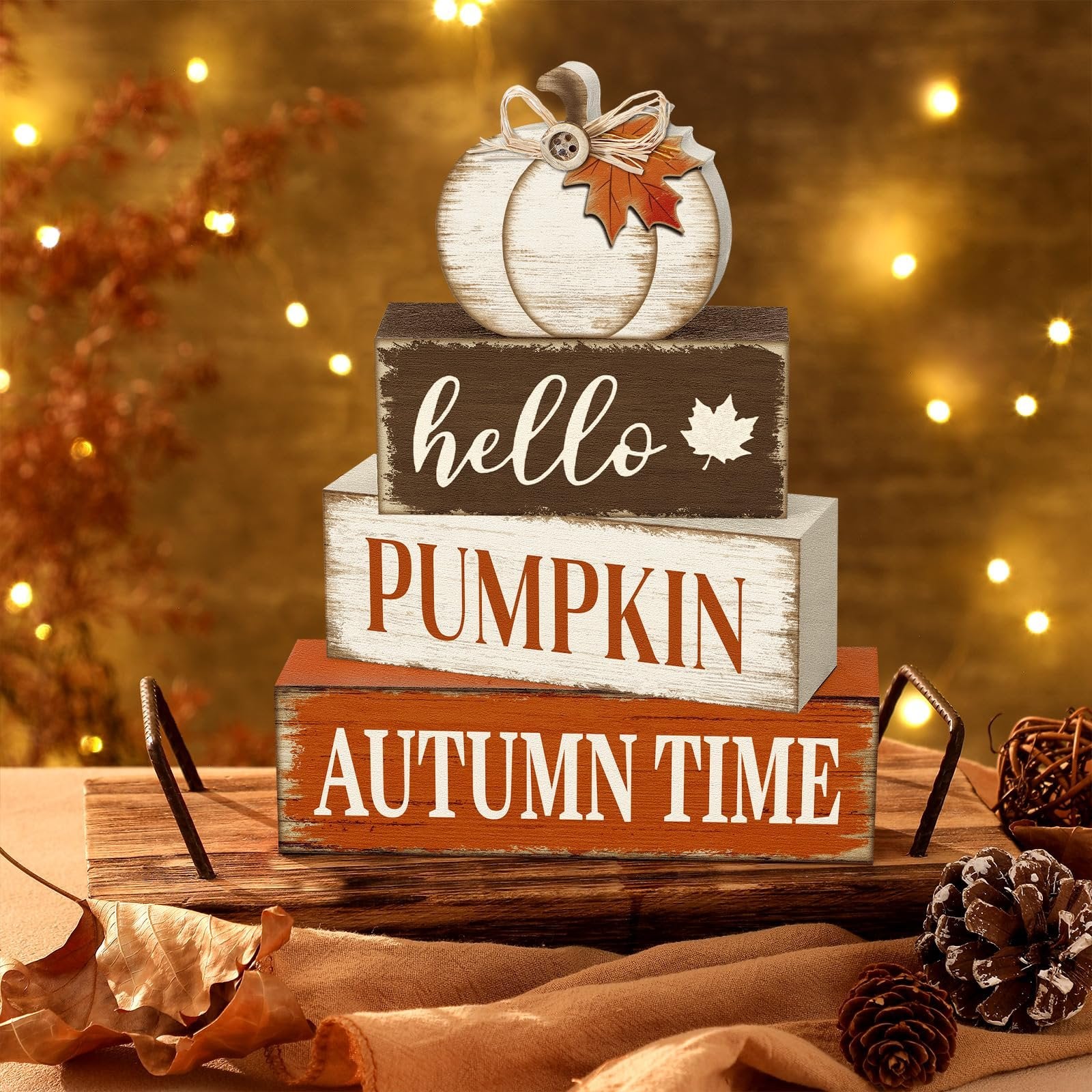 Stack of three wooden autumn signs with a decorative pumpkin on top, set on a tray with pinecones and leaves.