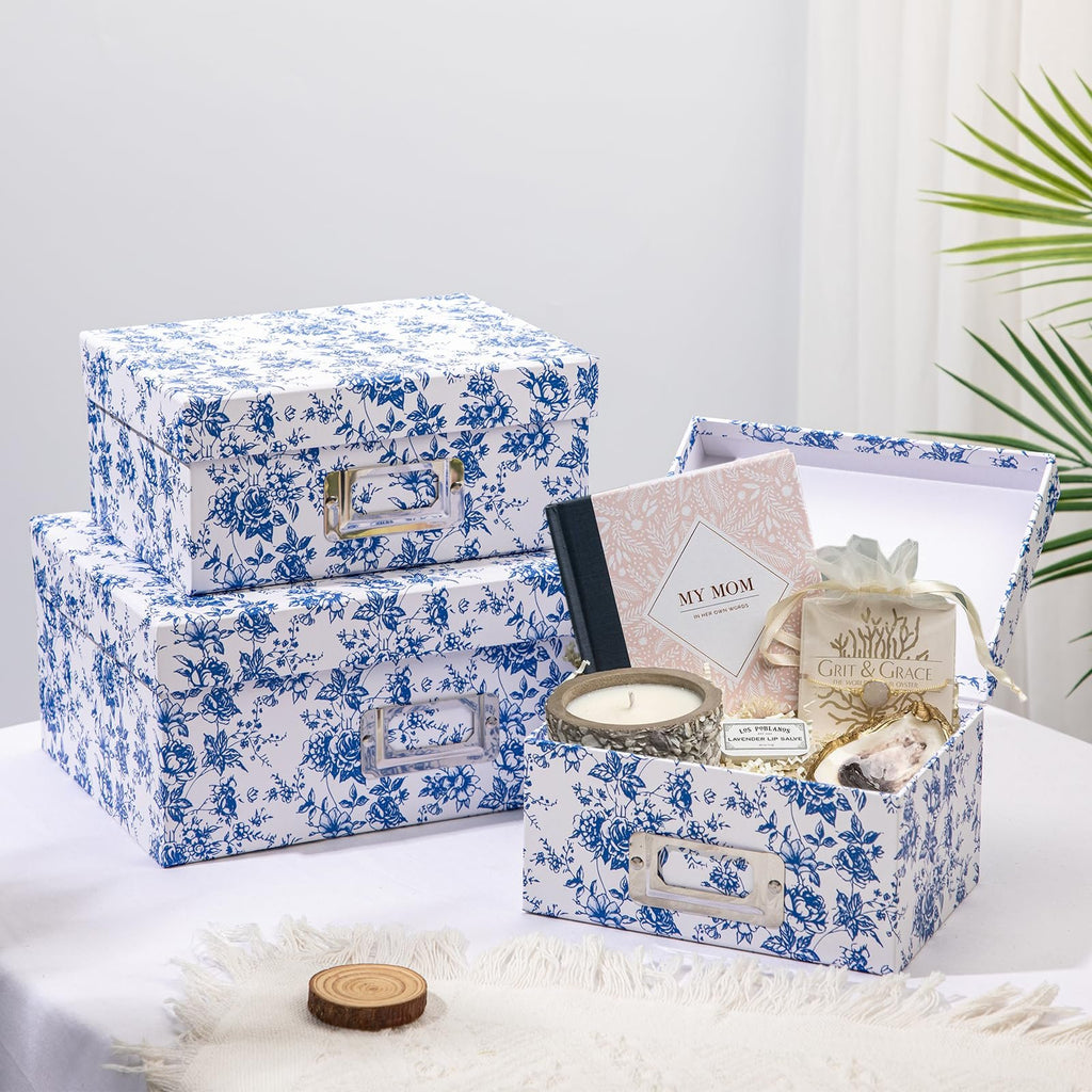 Set of blue and white floral storage boxes, one open showing contents like a candle, journal, and lip salve.