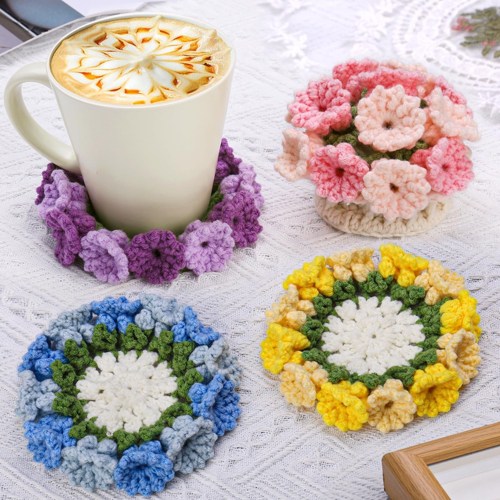 Four crocheted flower coasters with a mug of coffee on one, on a white textured surface.
