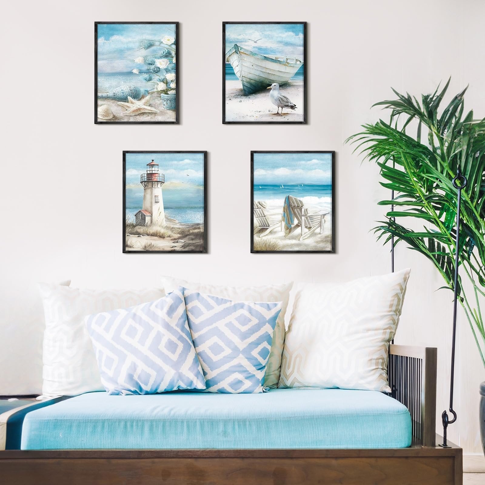 Four framed diamond art paintings depicting beach scenes with a boat, lighthouse, and chairs, displayed on a wall above a blue couch with pillows.