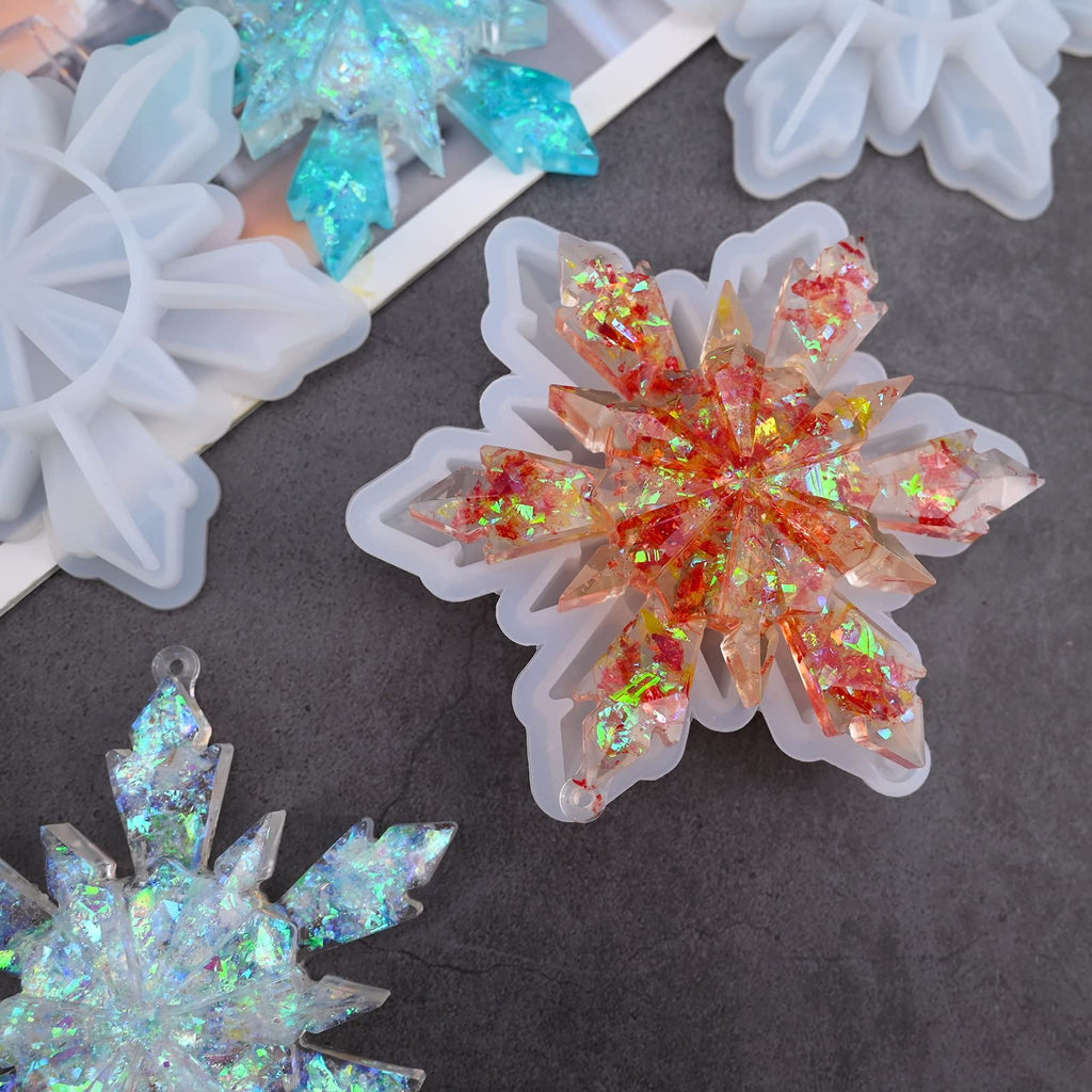 Silicone snowflake molds with finished resin ornaments in red and blue glitter, top view