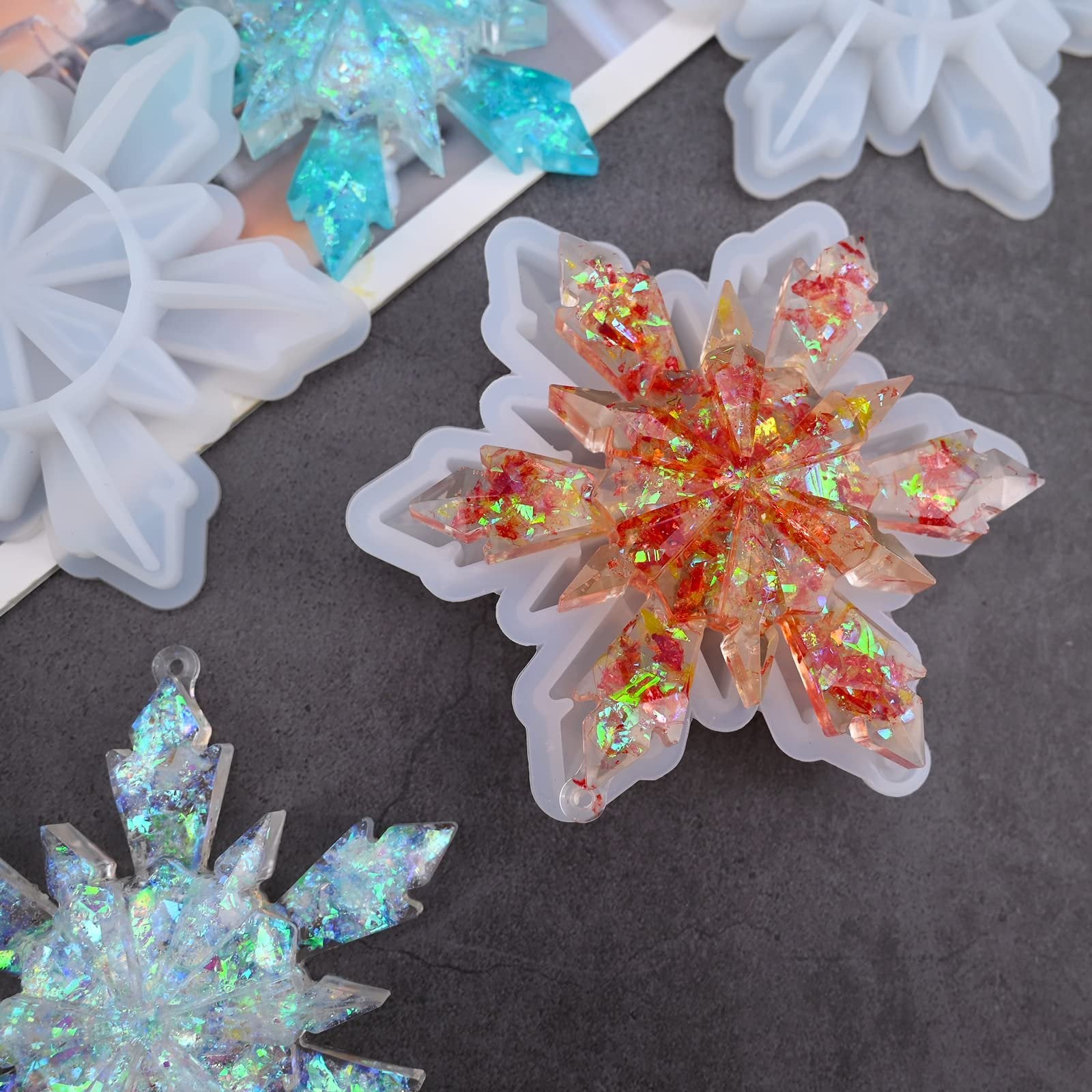 Silicone snowflake molds with finished resin ornaments in red and blue glitter, top view