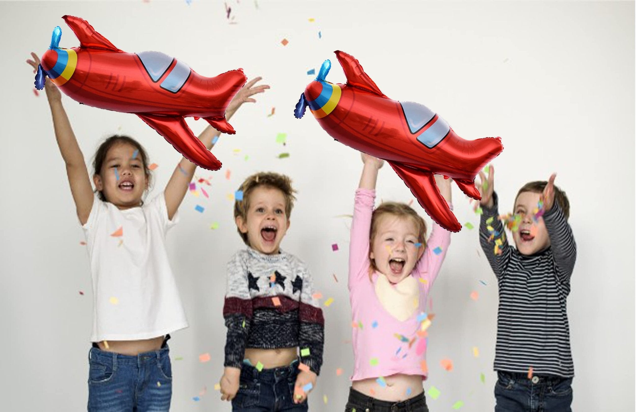 Four children holding red airplane foil balloons and throwing confetti