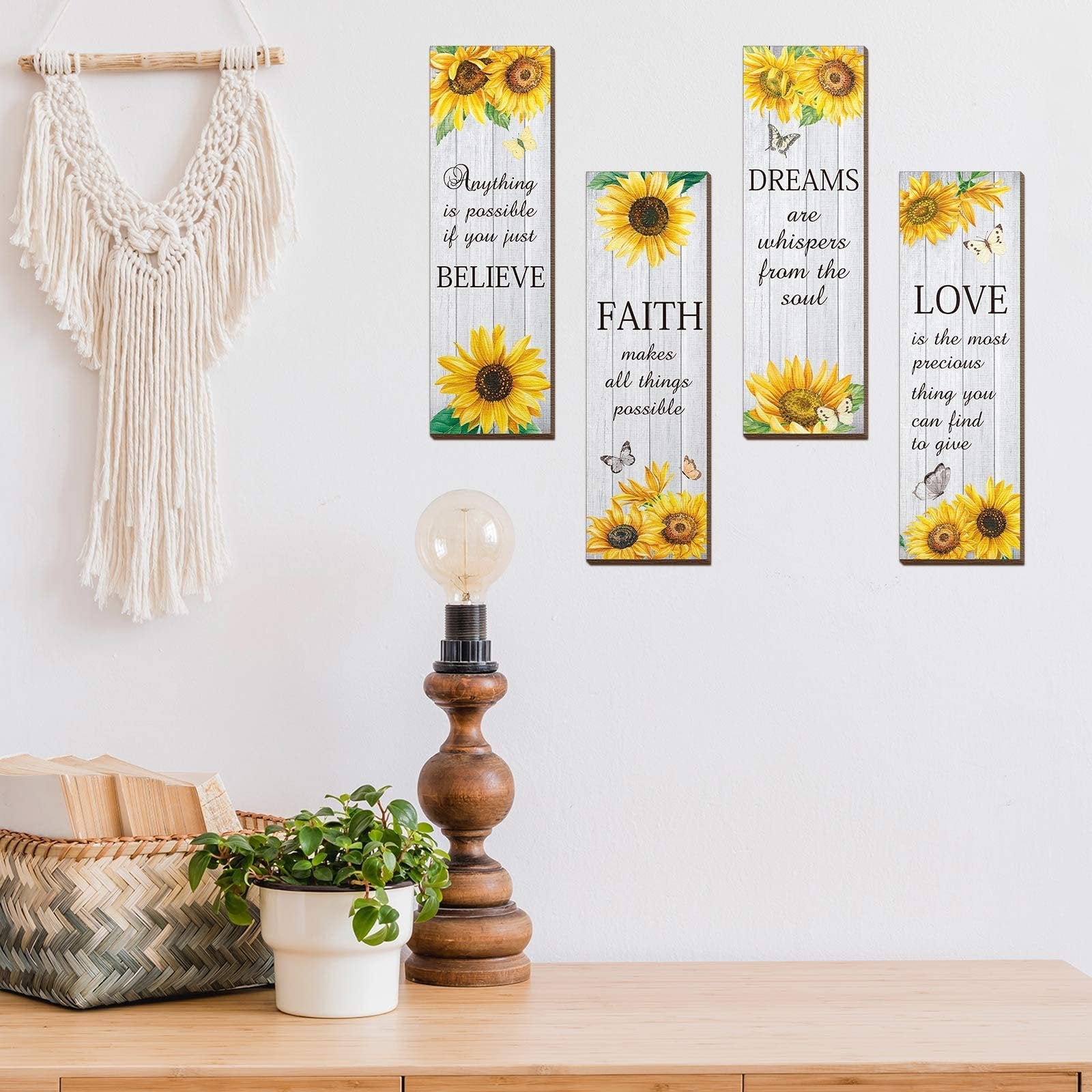 Four vertical wooden wall decor pieces with sunflowers and inspirational quotes, displayed on a wall above a wooden table.