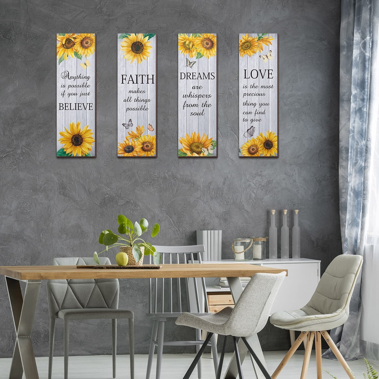 Four vertical wooden wall decor pieces with sunflowers and inspirational quotes hanging on a textured gray wall above a dining table.