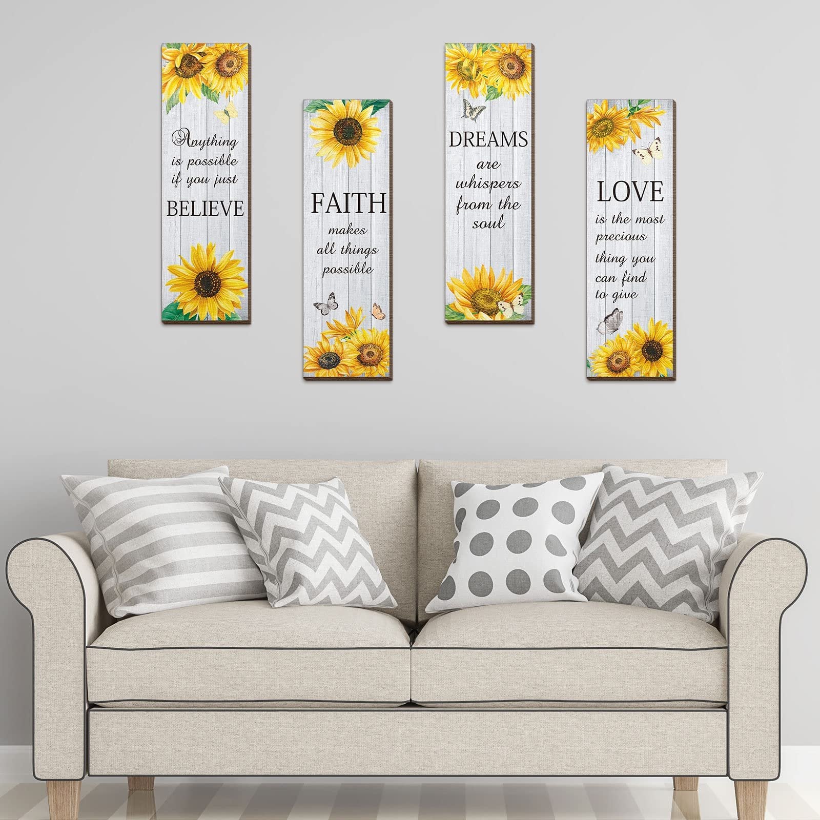 Four wooden wall decor pieces with sunflowers and inspirational quotes displayed above a sofa.