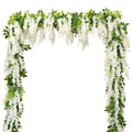 White wisteria garland with green leaves draped in an arch shape against a white background