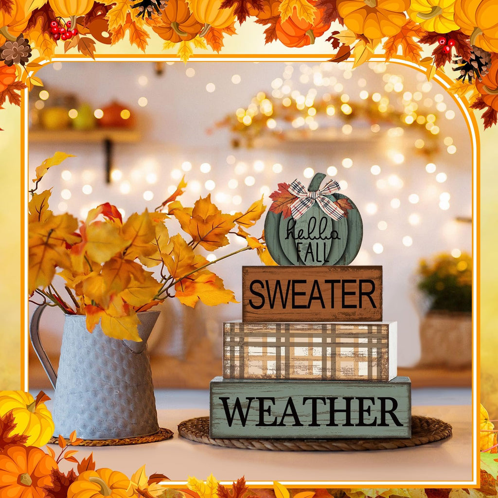 Fall-themed wooden decor set with a pumpkin sign and three book stack blocks reading 'SWEATER WEATHER' on a table with autumn leaves.