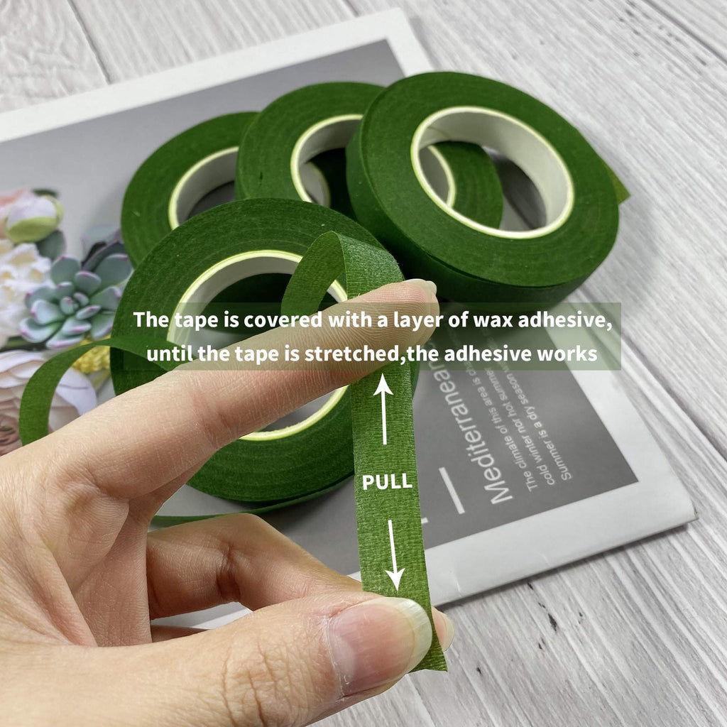 Hand stretching dark green floral tape, showing adhesive property. Four rolls of tape are visible in the background.