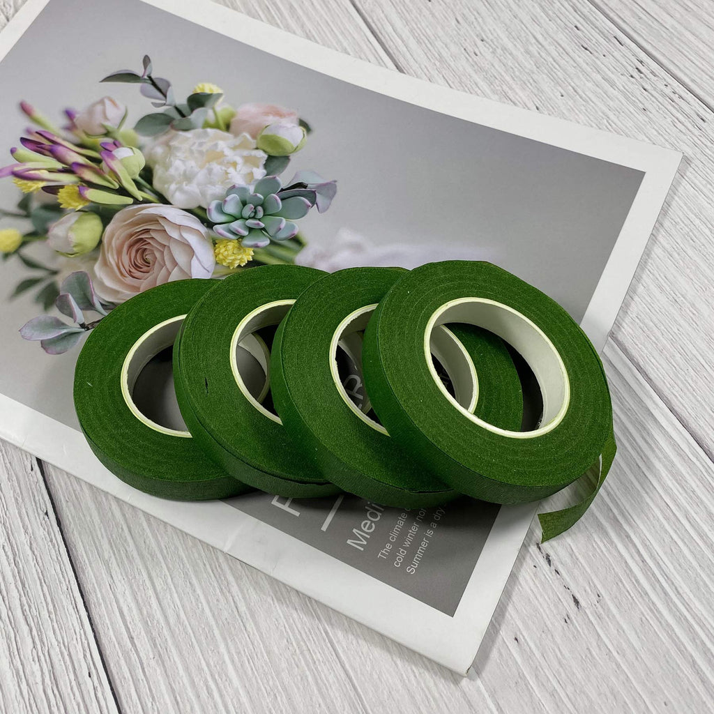 Four rolls of dark green floral tape arranged on a magazine with a floral arrangement pictured on it.