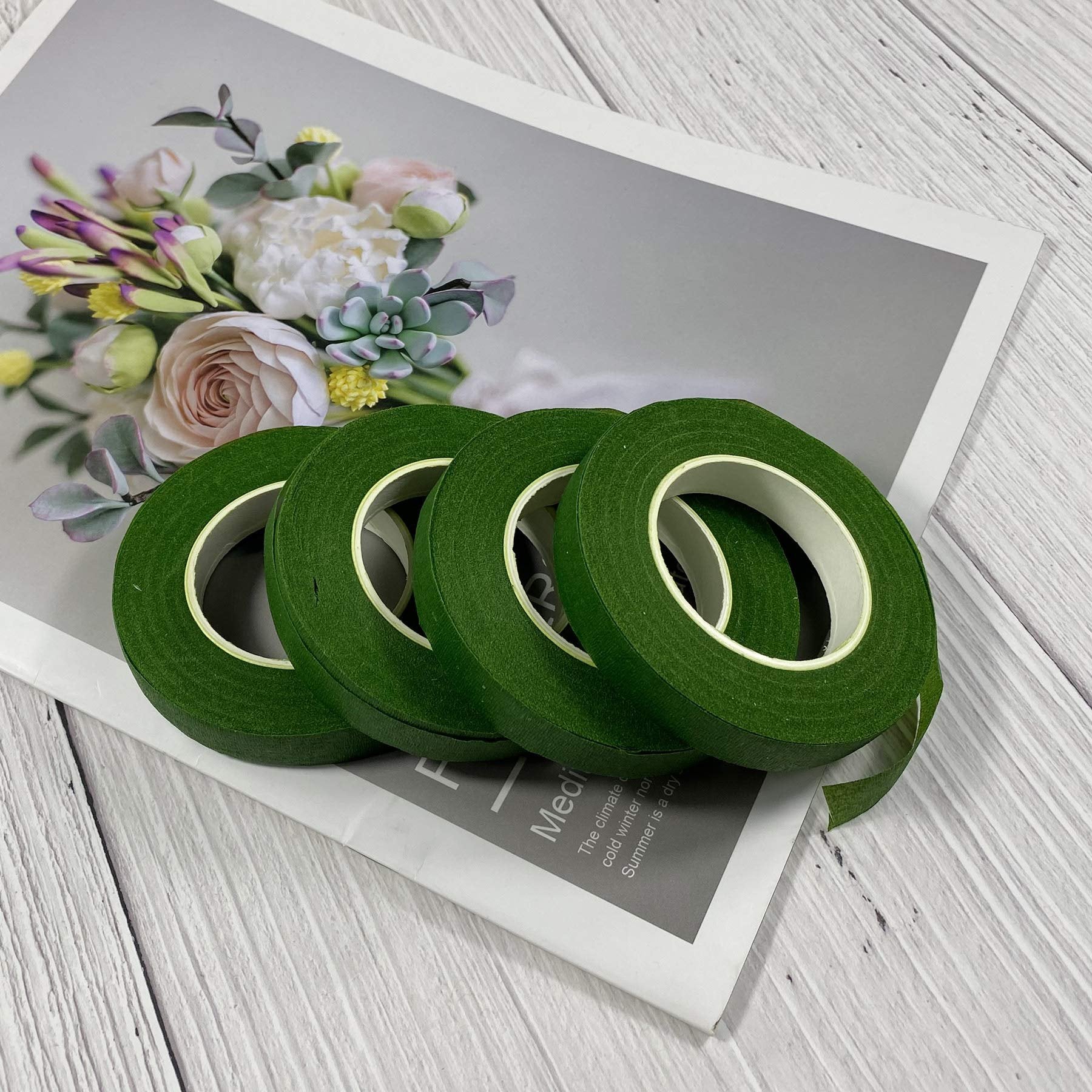 Four rolls of dark green floral tape arranged on a magazine with a floral arrangement pictured on it.