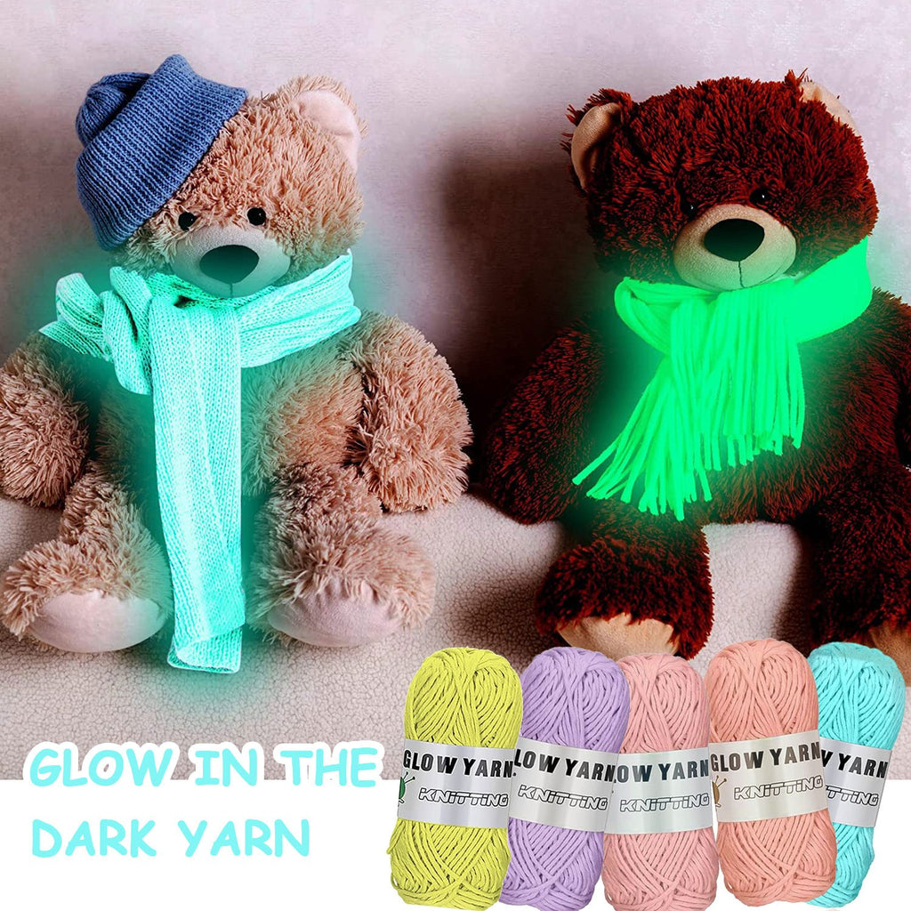 Two teddy bears wearing scarves and hats made from glow-in-the-dark yarn, with balls of yarn in foreground.