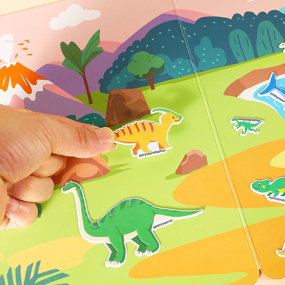 Toddler placing a dinosaur sticker labeled parasaurolophus onto a colorful scene in a sticker book.