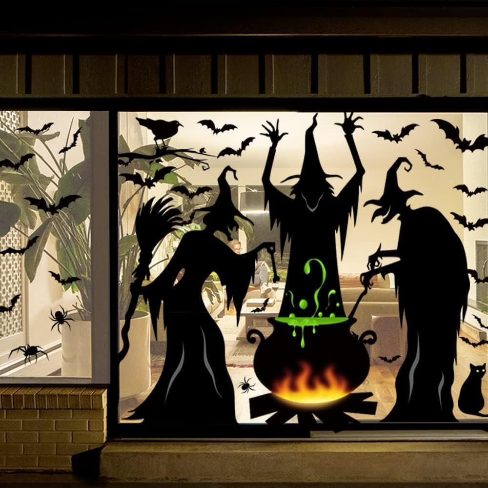 Halloween window clings featuring three witches around a cauldron with bats and spiders, applied to a large window.