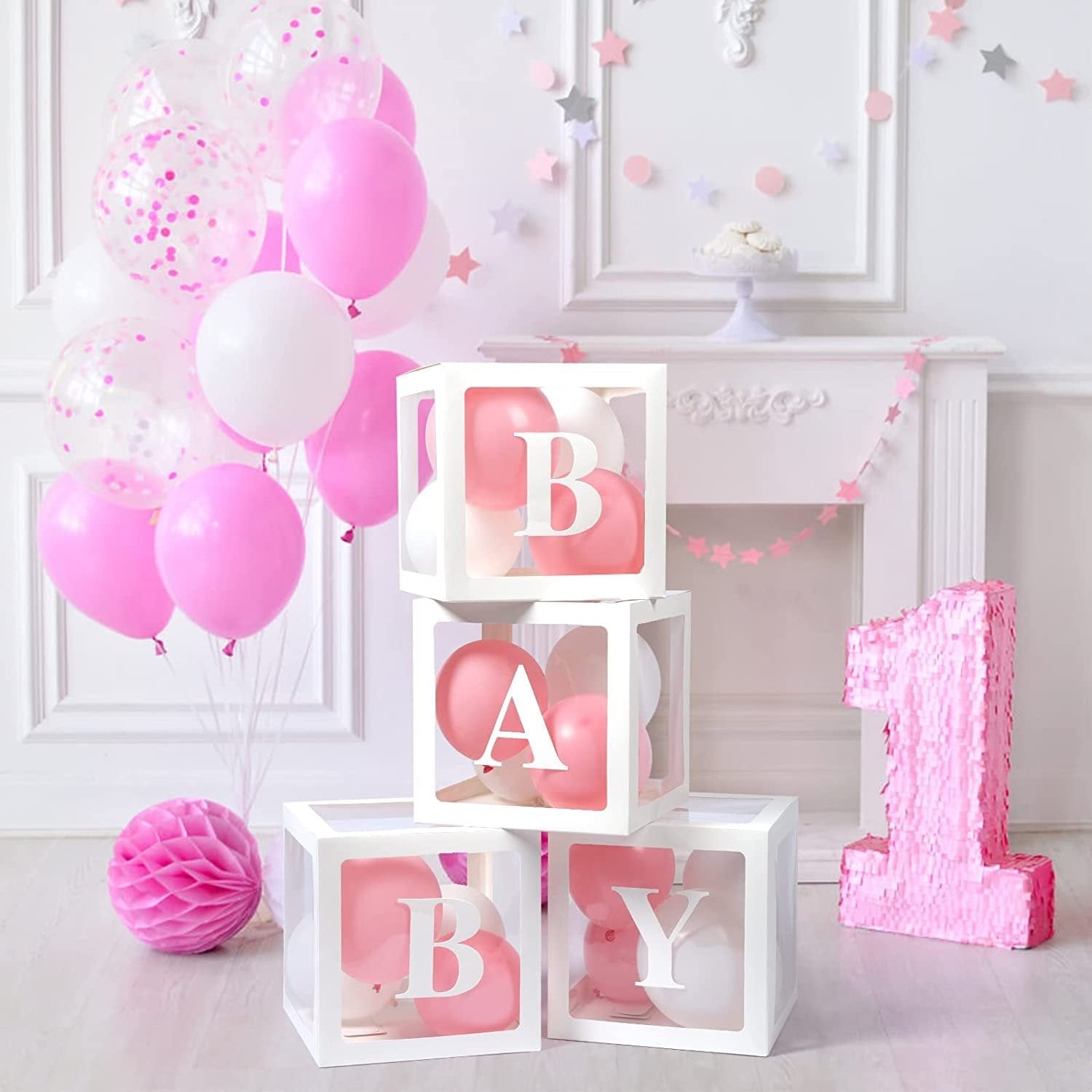 Four transparent white boxes with pink and white balloons inside, spelling BABY, next to a large pink sequined number 1.
