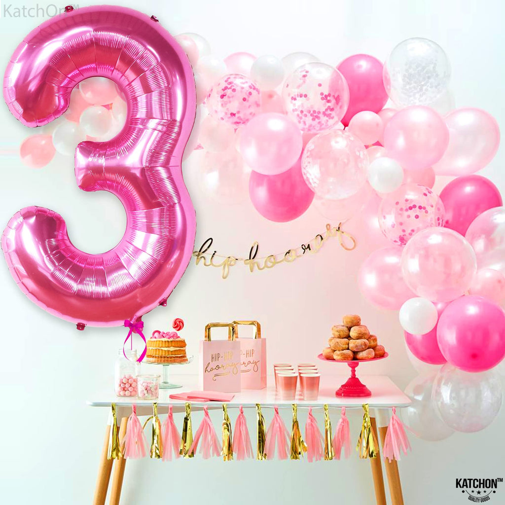 Large pink number 3 foil balloon with a party table setup including cake, donuts, and balloons.