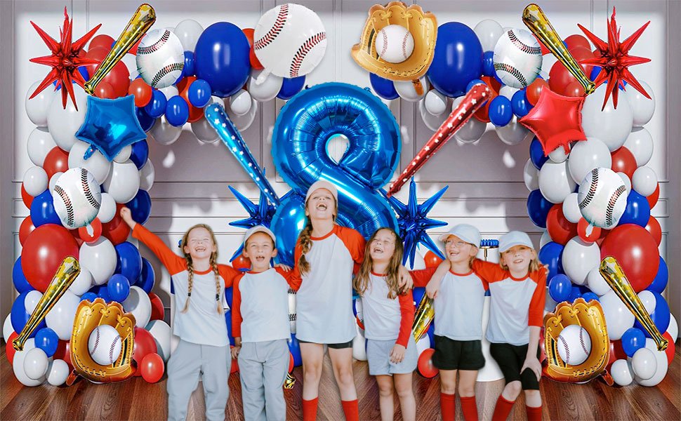 Children in baseball attire posing in front of a balloon arch featuring baseballs, bats, gloves, and a large number 7 balloon.