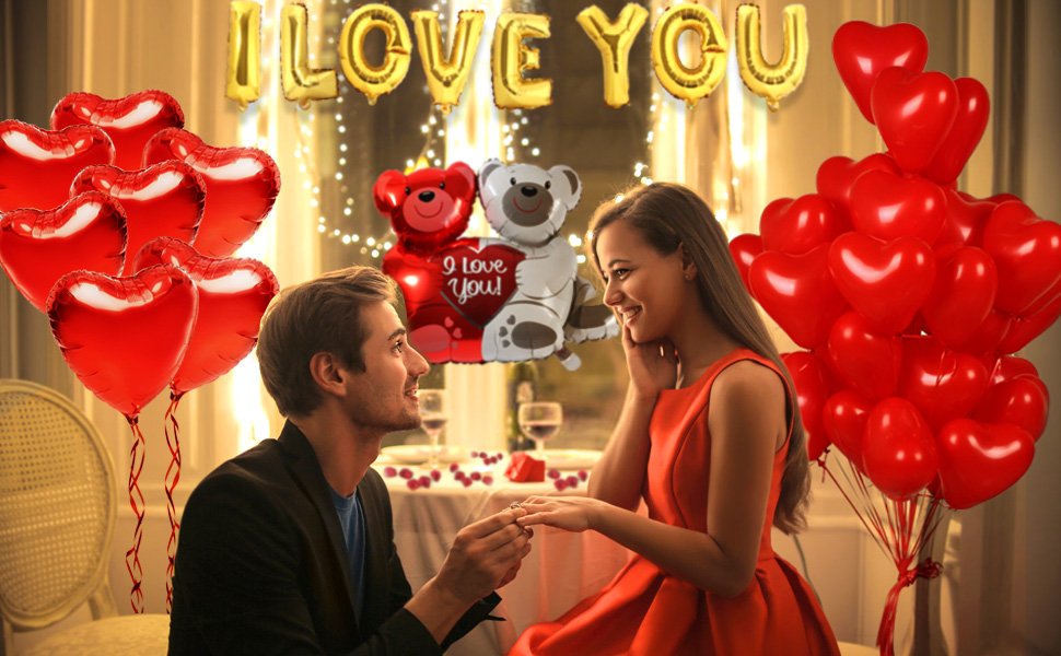 Couple celebrating Valentine's Day with heart and letter balloons, man proposing to woman