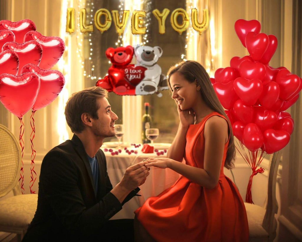 Couple celebrating Valentine's Day with heart balloons and 'I Love You' banner